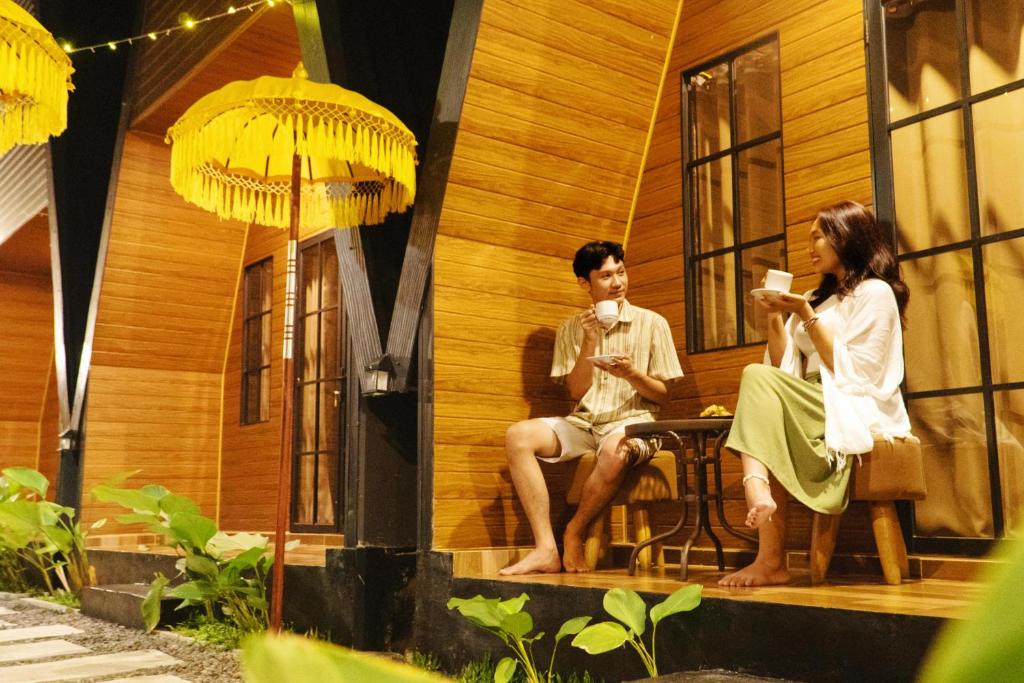 a man and woman sitting on the porch of a house at D'svarga Glamping in Seturan