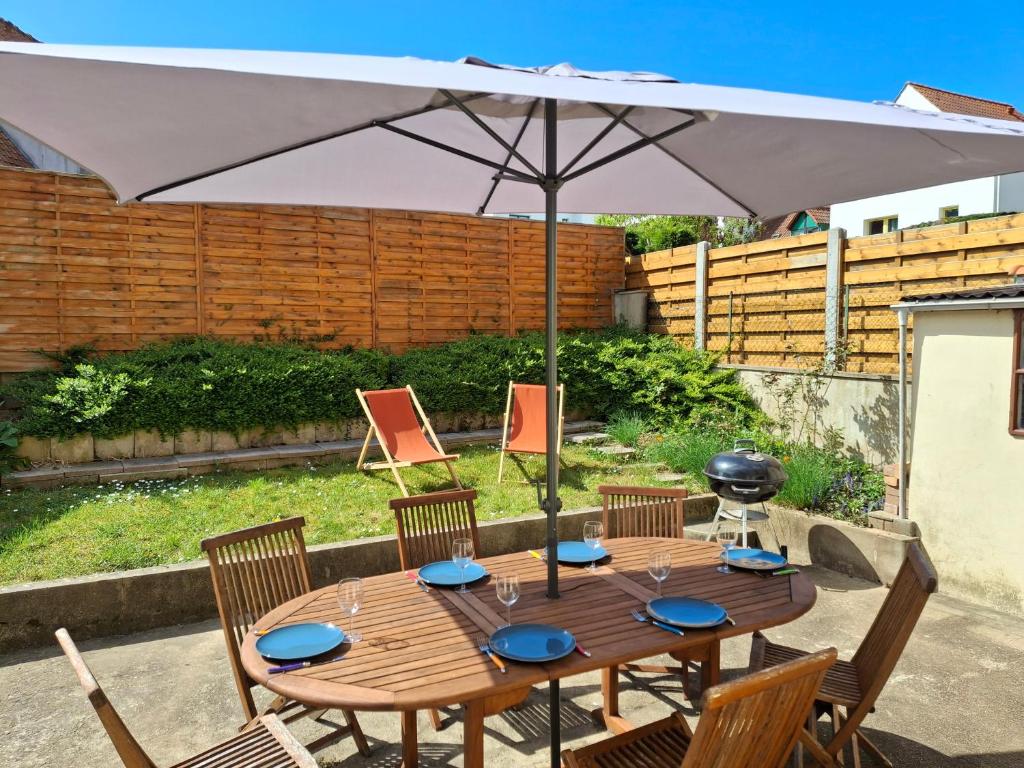 - une table en bois avec un parasol dans l'arrière-cour dans l'établissement Charmante maison 8 personnes à 2 pas de Wimereux, à Wimille
