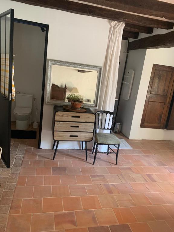 ein Zimmer mit einer Kommode, einem Spiegel und einem Stuhl in der Unterkunft Maison de charme in Malicorne-sur-Sarthe