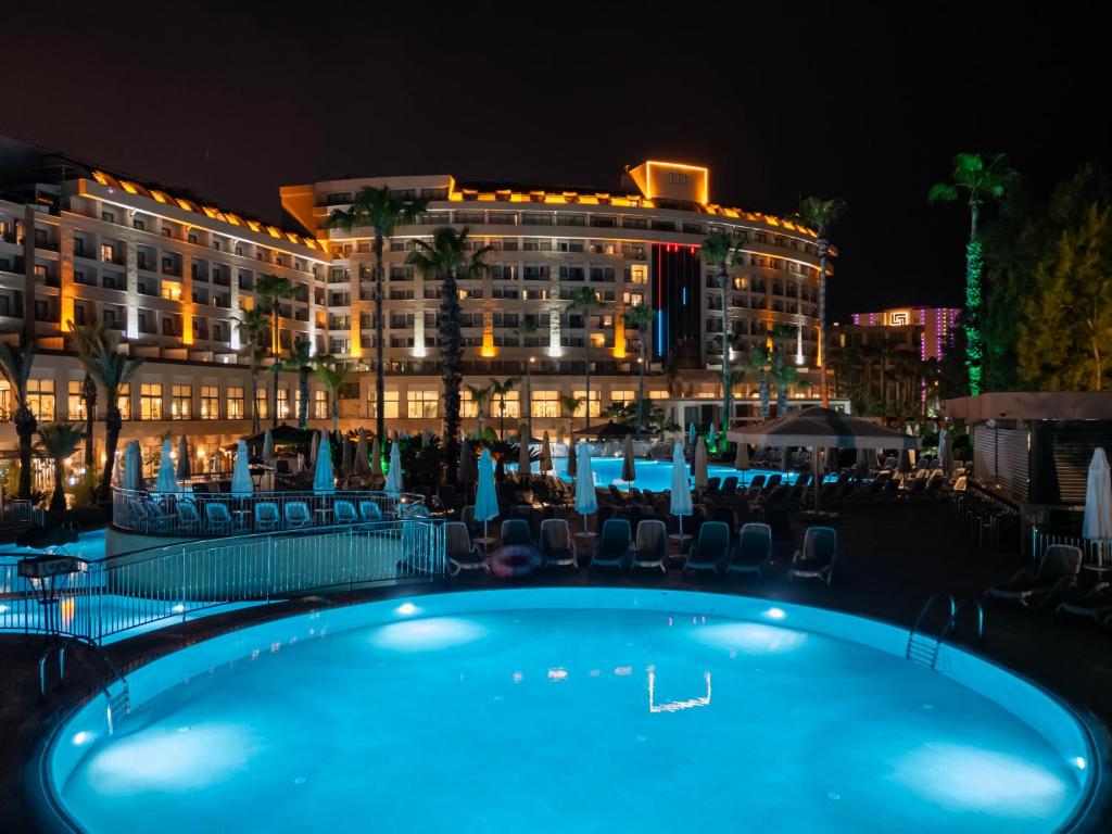 a swimming pool in front of a hotel at night at Fame Residence Lara & Spa in Lara