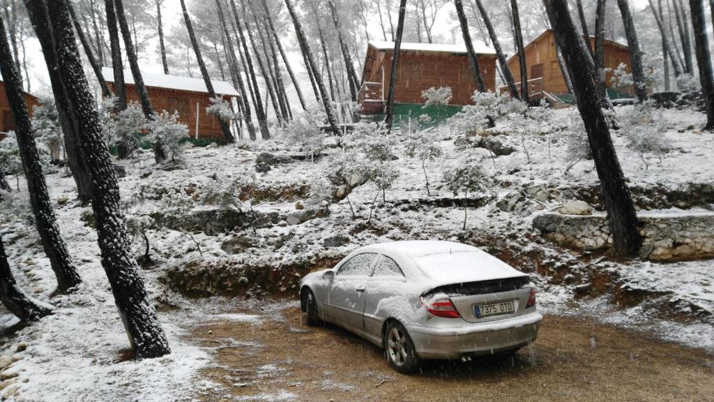 samochód zaparkowany w śniegu w lesie w obiekcie Cabañas El Robledo w mieście El Robledo