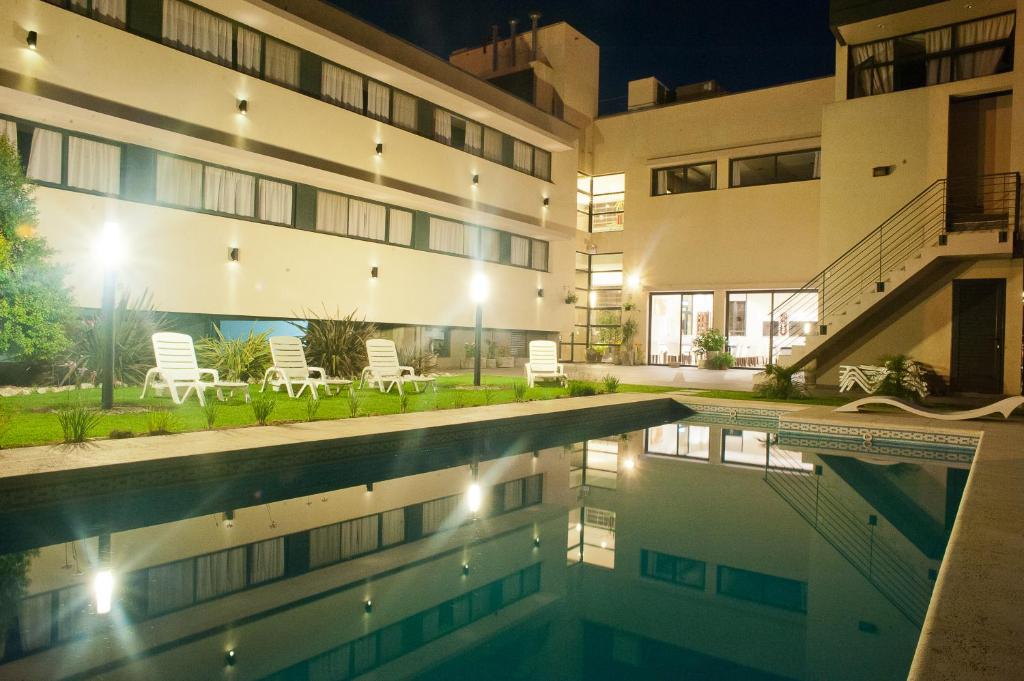 - une piscine en face d'un bâtiment la nuit dans l'établissement Hotel Portal del Este, à Marcos Juárez