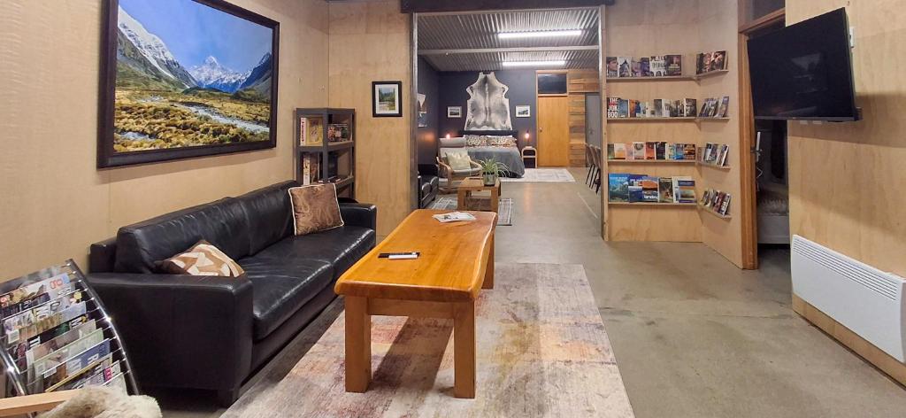 a living room with a black leather couch and a table at Blue Mountains Loft, Tapanui in Glenkenich