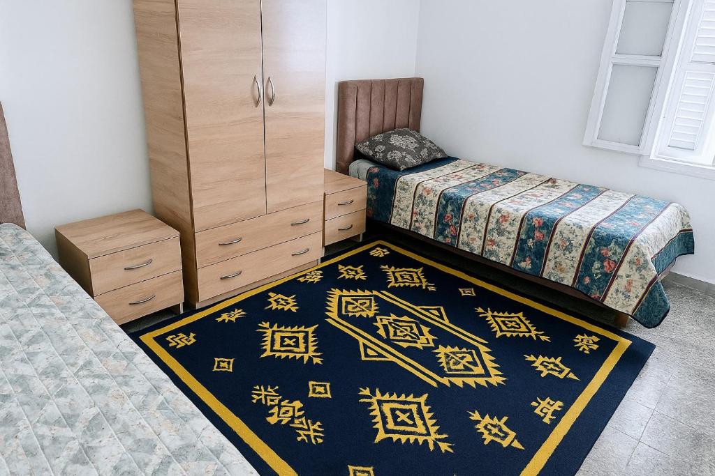 a bedroom with two beds and a cabinet and a rug at Maison Fleur in La Goulette