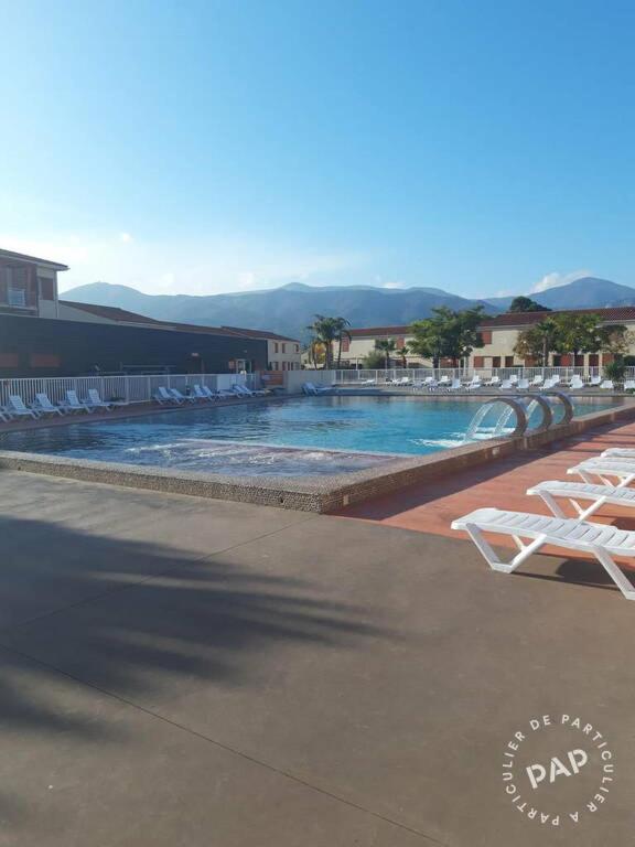 une grande piscine avec des chaises longues dans un complexe dans l'établissement Maison de Vacances dans résidence Privée, à Argelès-sur-Mer