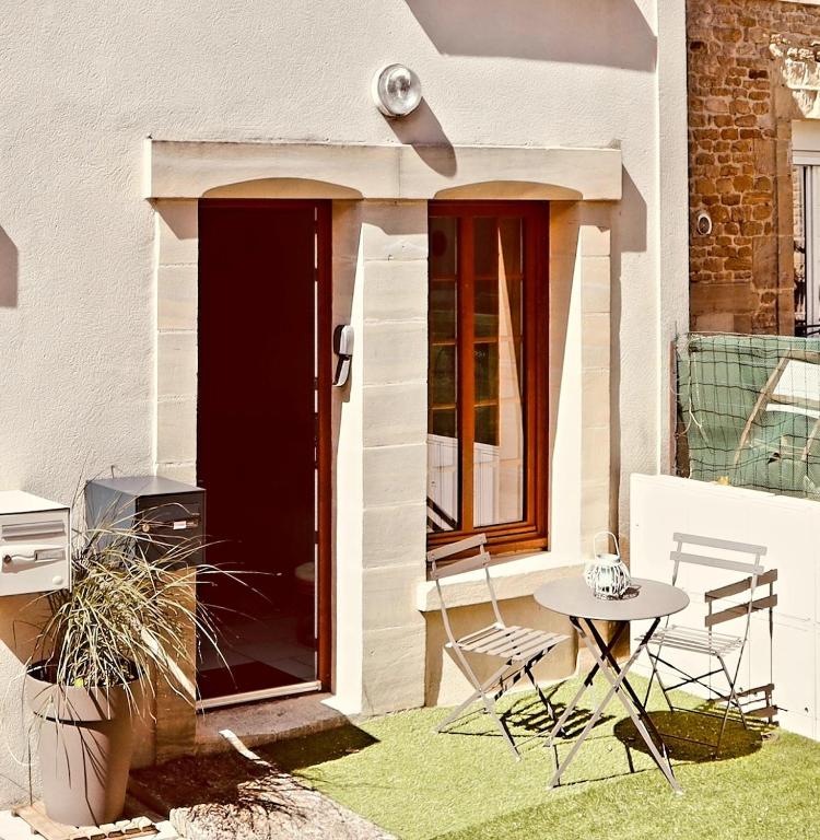 un patio avec une table et des chaises sur l'herbe dans l'établissement Maison de ville Côte de Nacre, à Douvres-la-Délivrande