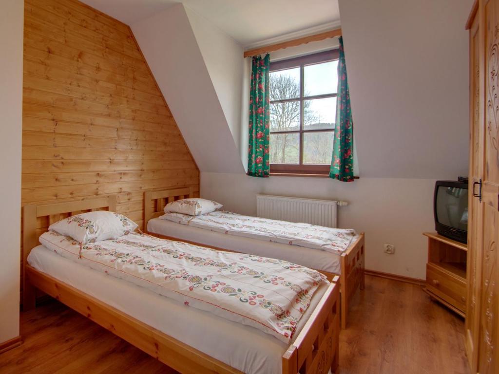 two beds in a room with a window and a tv at Apartament Krupówki 73 - 2-7 person in Zakopane