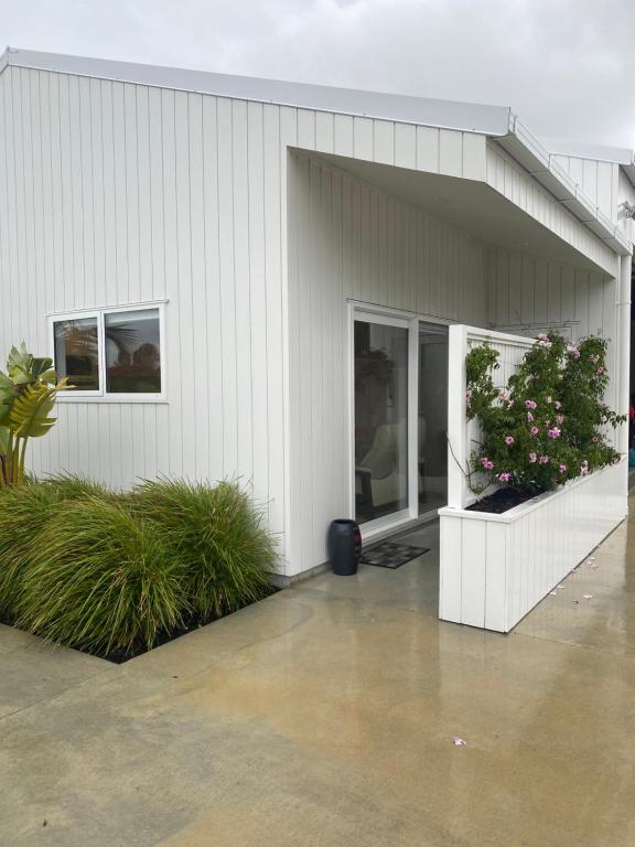 a white building with two windows and two plants at Point Wells Holiday Apartment in Big Omaha