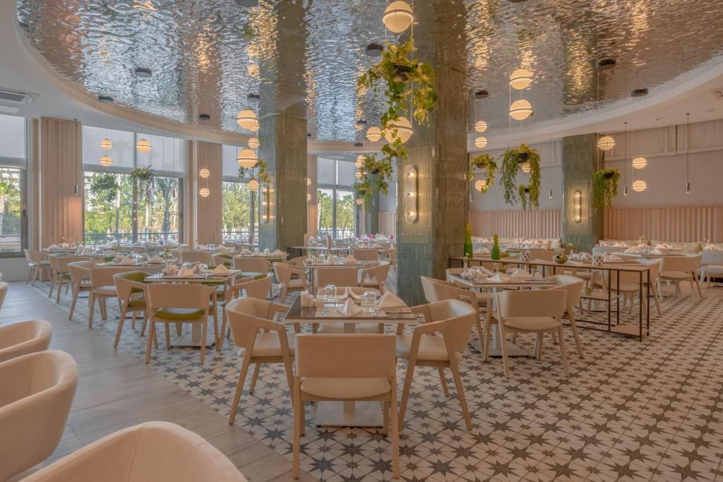 a dining room with tables and chairs and chandeliers at Fame Residence Lara & Spa in Lara