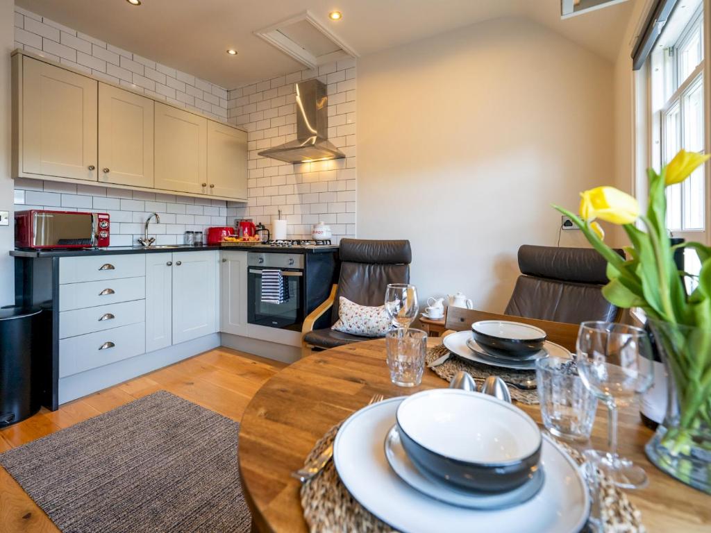 una cucina e una sala da pranzo con tavolo in legno e piatti di Pass the Keys Bright and cosy flat in the centre of Much Wenlock a Much Wenlock