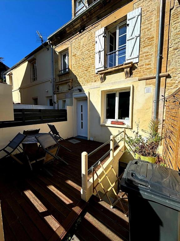 une maison dotée d'une terrasse avec des chaises et d'un bâtiment dans l'établissement Maison terrasse proche mer, à Douvres-la-Délivrande