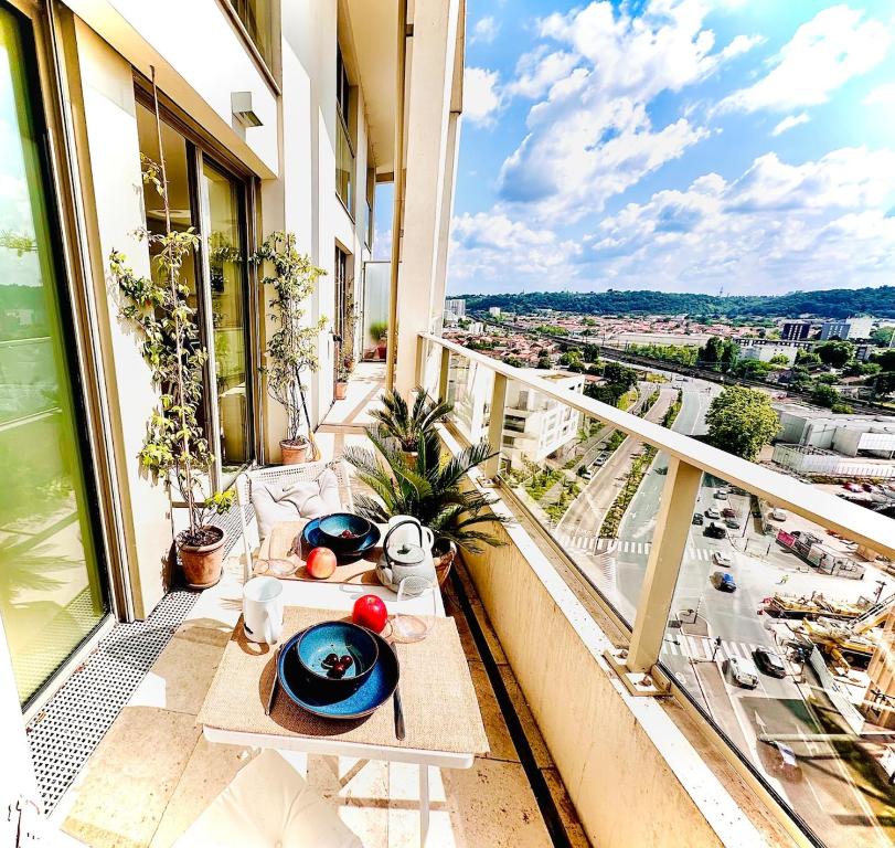un balcon avec une table et une vue sur une ville dans l'établissement Duplex Avec Terrasse Dans Le Ciel Bordelais, à Bordeaux