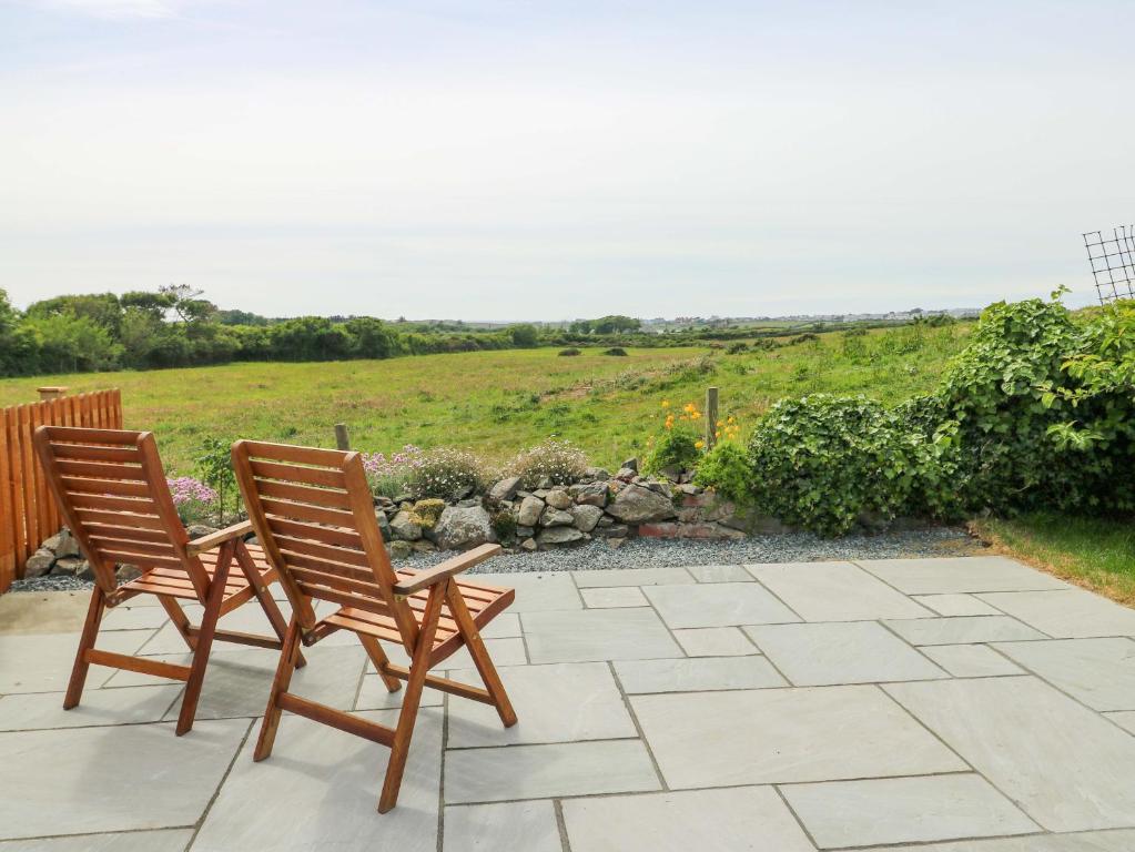 two chairs sitting on a patio with a field at Ty Bach in Rhosneigr