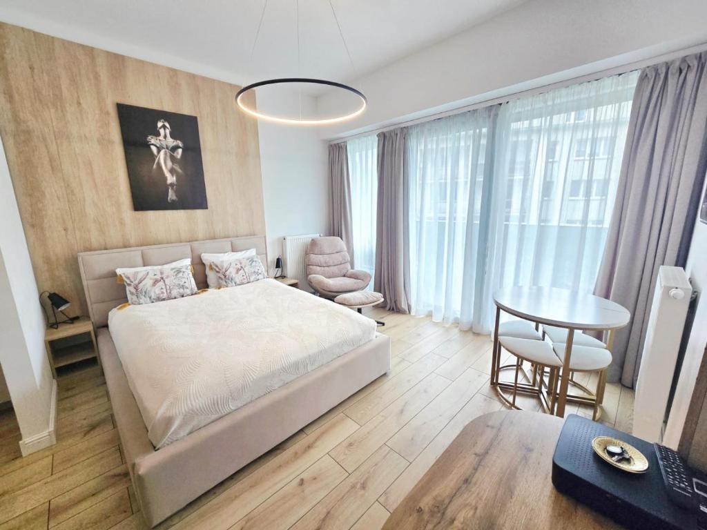 a bedroom with a bed and a table and a chair at Hanza Tower AJP Jaccuzi SPA apartament in Szczecin