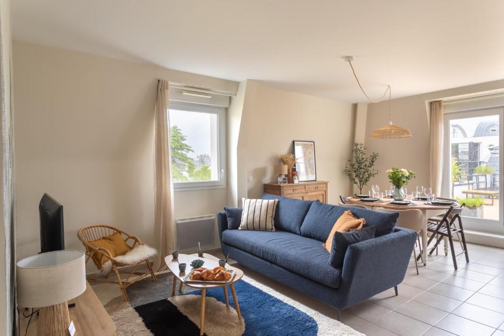 un salon avec un canapé bleu et une table dans l'établissement Kerlibri - 15min à Pied de la Plage, à Dinard