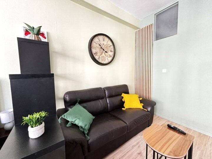 Una sala de estar con un sofá y un reloj en la pared. en Joli studio hypercentral, en Saint-Claude