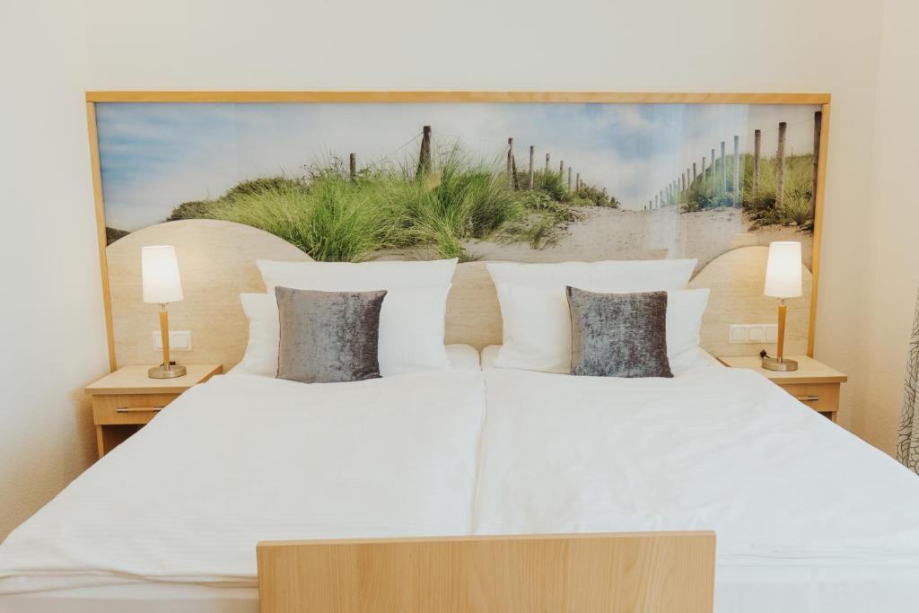 ein Schlafzimmer mit einem weißen Bett und einem Gemälde an der Wand in der Unterkunft Parkhotel IV Jahreszeiten Kühlungsborn in Kühlungsborn