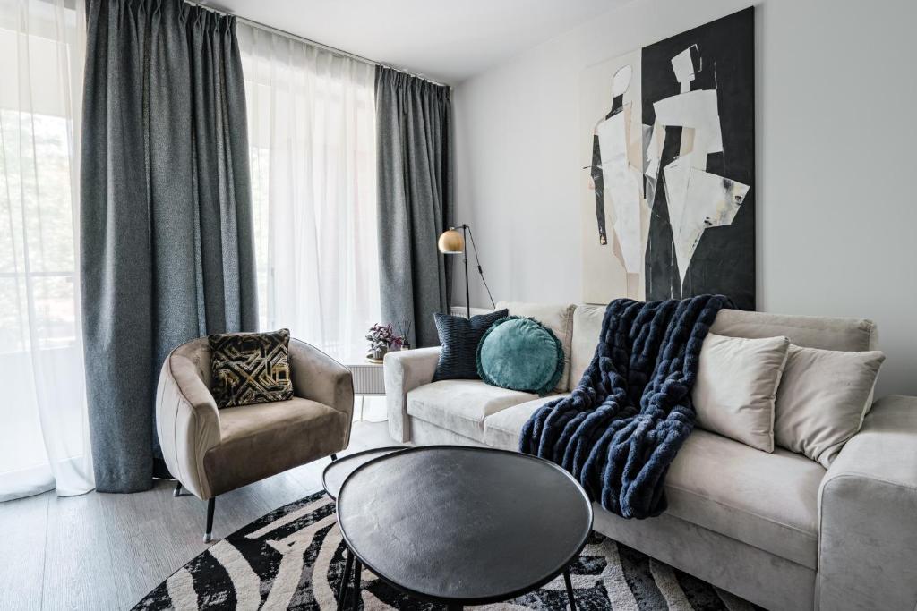 Hotel Scala City Center Apartments with Parking by Lion Apartments, a living room with a couch and a table and a chair at Scala City Center Apartments with Parking by Lion Apartments in Gdańsk