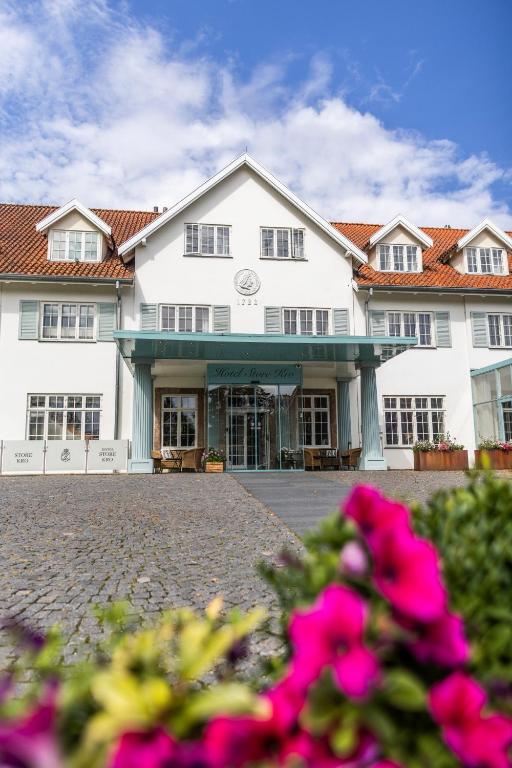 a large white building with pink flowers in the foreground at Hotel Fredensborg Store Kro in Fredensborg