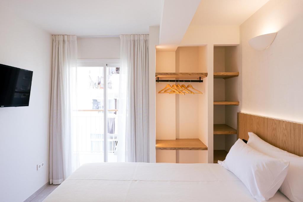 a bedroom with a white bed and a window at Malacosta A - MC Apartments Ibiza in Ibiza Town