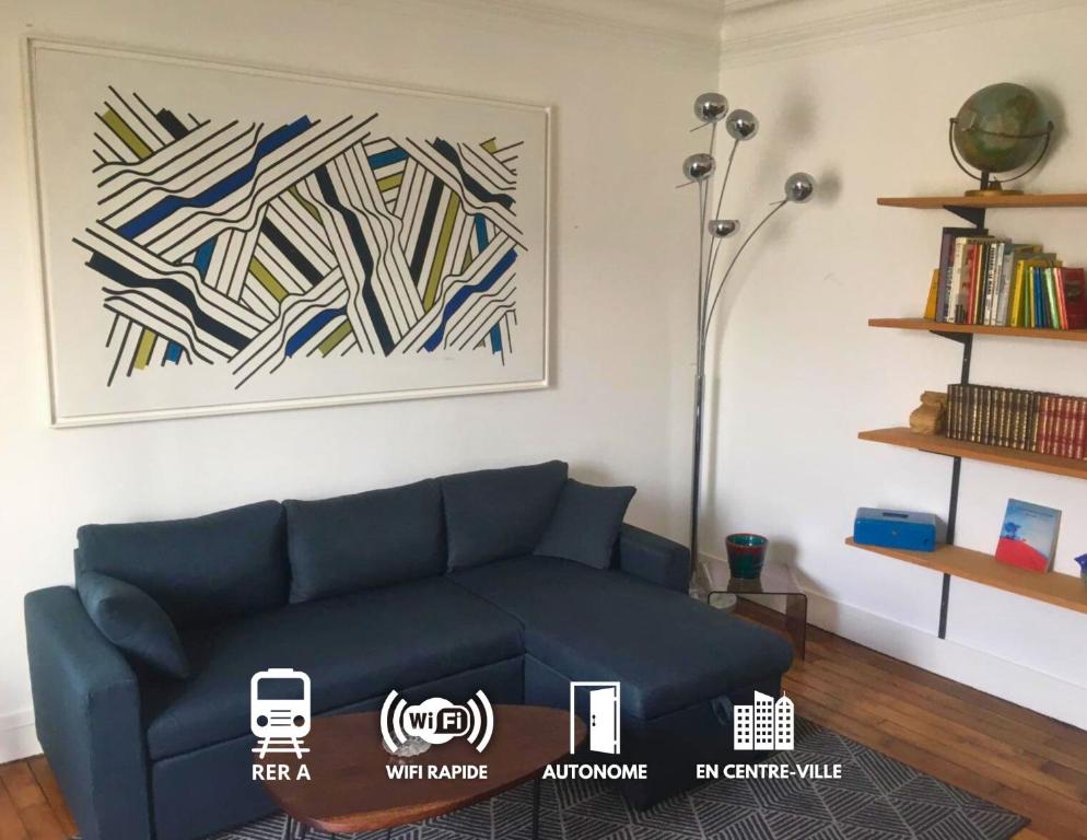 ein Wohnzimmer mit einem blauen Sofa und einem Gemälde in der Unterkunft T2 plein centre-ville, Gare à 5 min, Près Ermitage in Maisons-Laffitte