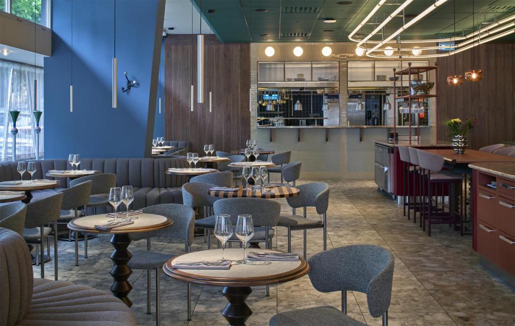 a restaurant with tables and chairs and a blue wall at Scandic Malmen in Stockholm