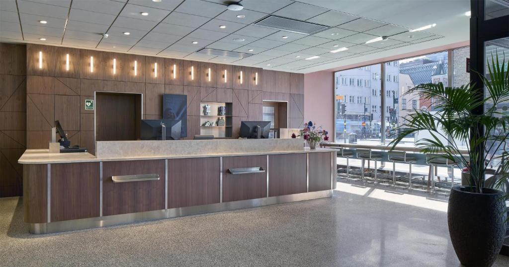 a lobby with a reception desk and a large window at Scandic Malmen in Stockholm