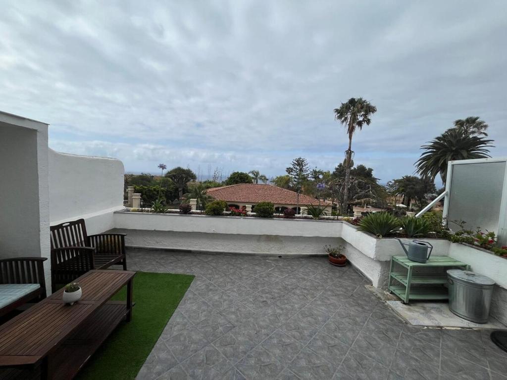 a patio with two benches and a balcony with palm trees at Sunset bungalow Oceanfront Relax in Los Realejos