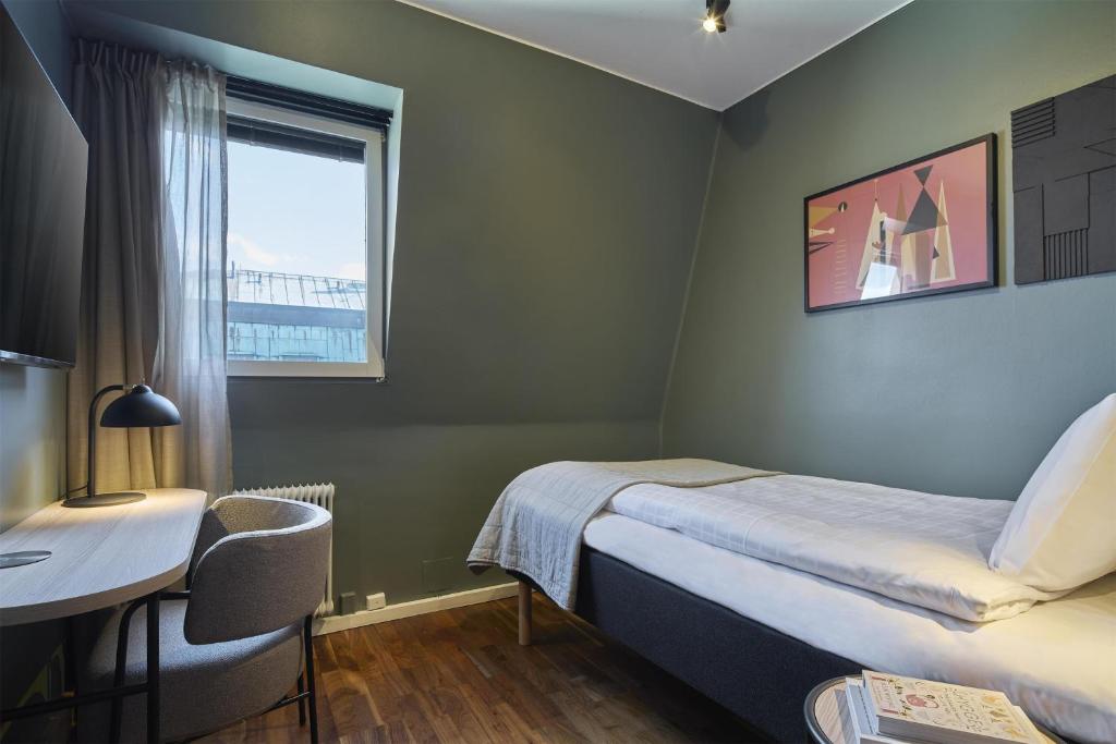 a bedroom with a bed and a desk and a window at Scandic Malmen in Stockholm