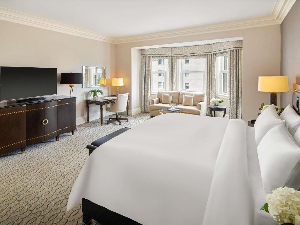 a bedroom with a large bed and a living room at Fairmont Chateau Laurier in Ottawa