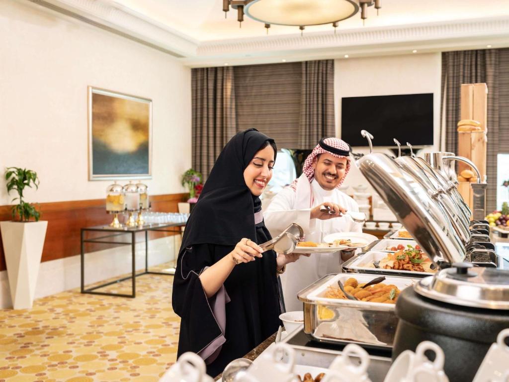 two women standing in a buffet line preparing food at Swissotel Al Maqam Makkah in Mecca