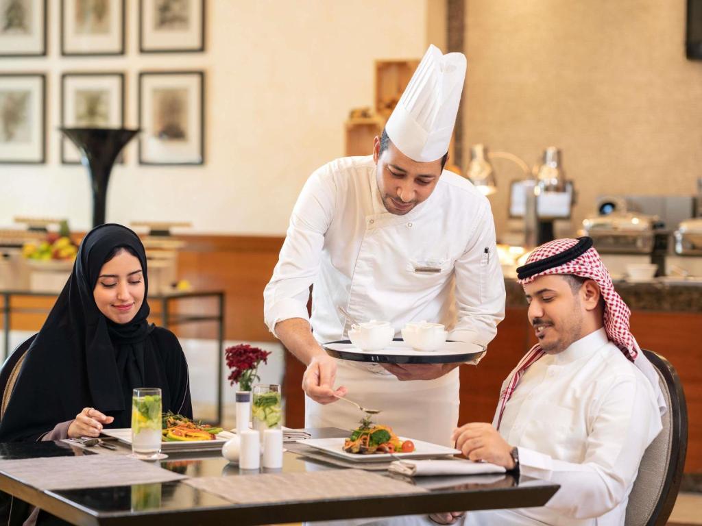 a chef preparing a plate of food in a restaurant at Swissotel Al Maqam Makkah in Mecca