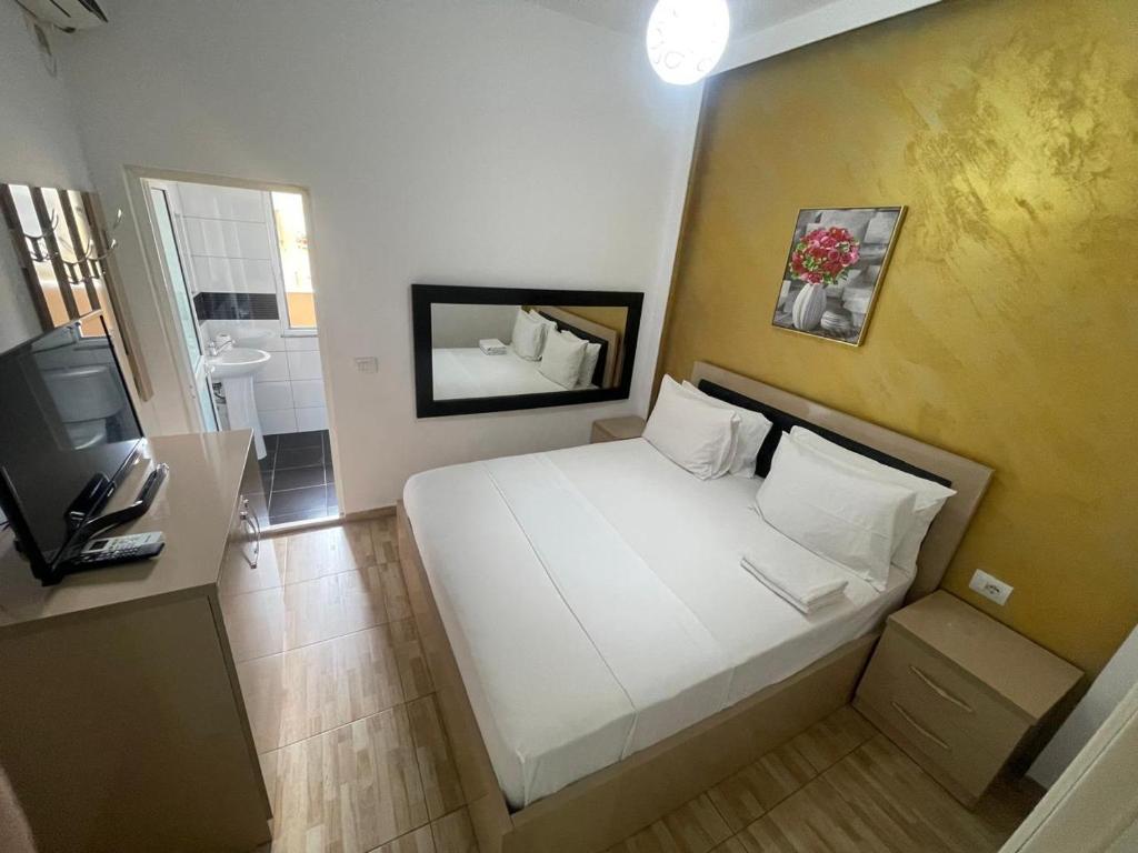 Dormitorio pequeño con cama blanca y TV en Hotel Fabio, en Tirana