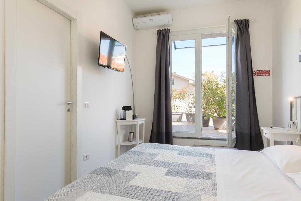 Dormitorio blanco con cama y puerta corredera de cristal en La Terrazza, en Rho