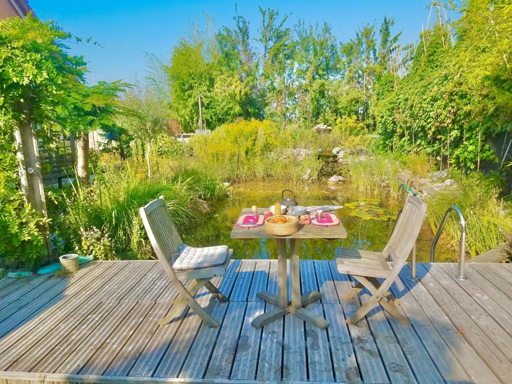 une terrasse en bois avec une table et deux chaises dans l'établissement La Secrète en Alsace, Gîte familial spacieux avec jardin clos, proche Colmar & Route des Vins, à Algolsheim
