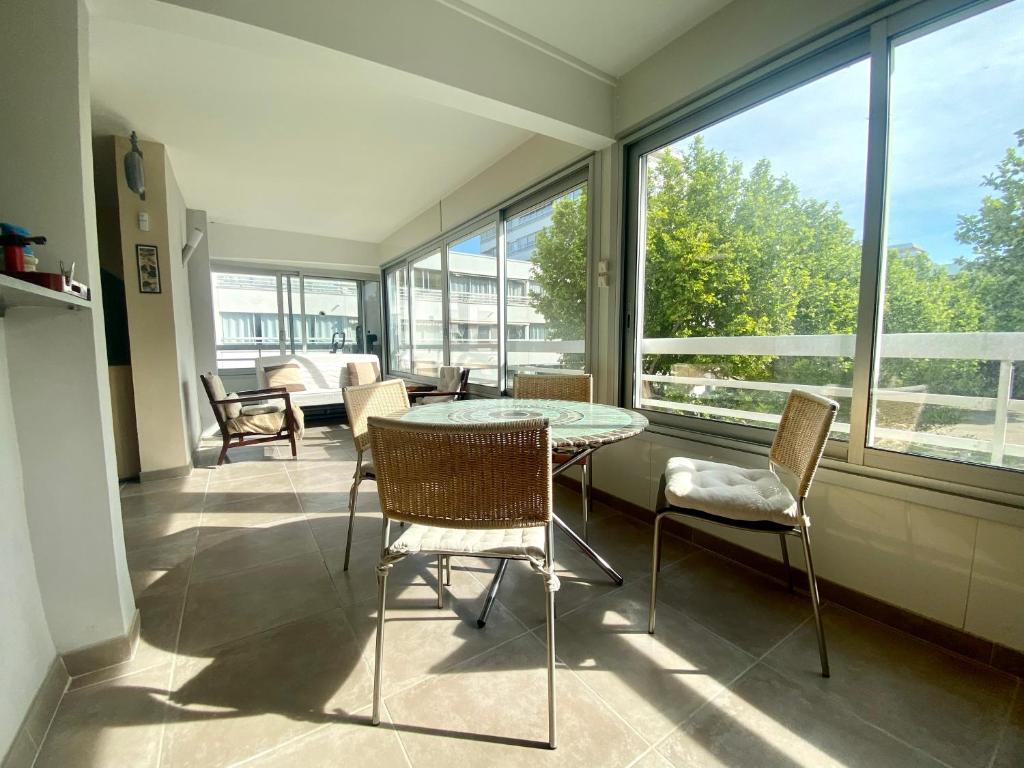 une pièce avec une table, des chaises et des fenêtres dans l'établissement Charmant Appartement Rénové pour 5 Personnes – Résidence avec Piscine et Parking – La Grande Motte, à La Grande Motte
