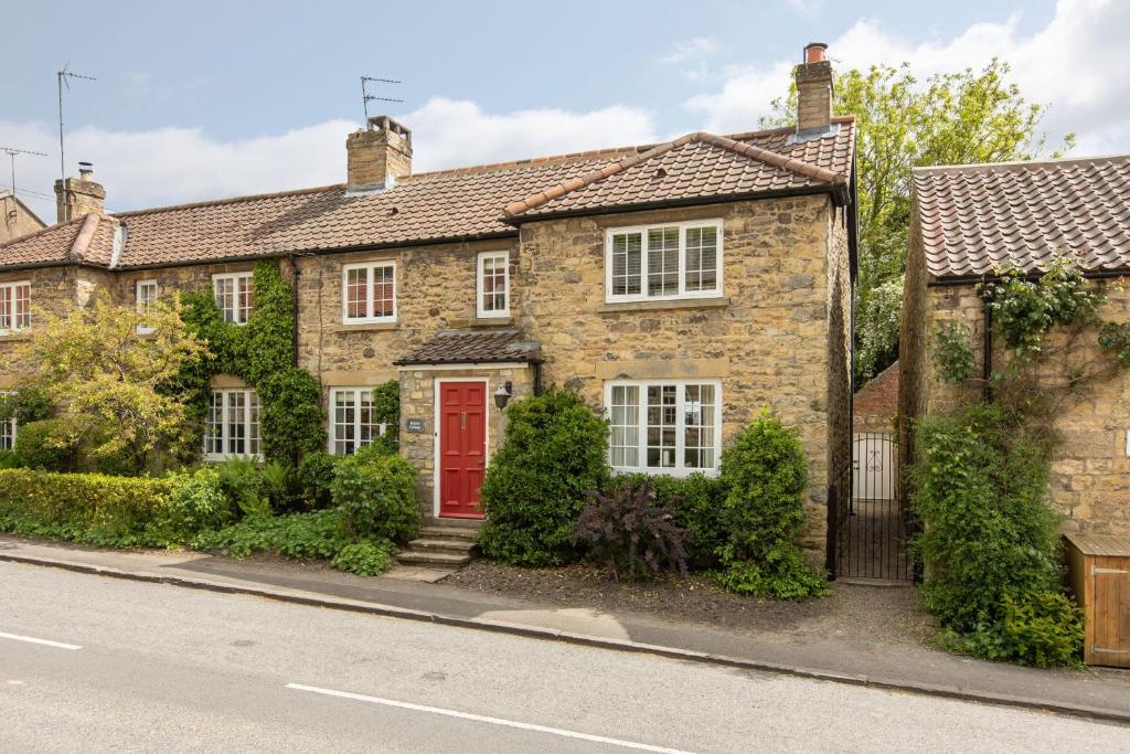 a brick house with a red door on a street at Robins Cottage in York