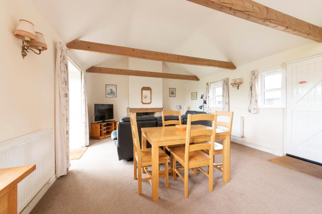 a dining room with a wooden table and chairs at Buckingham Cottage - Lancombes House in Powerstock