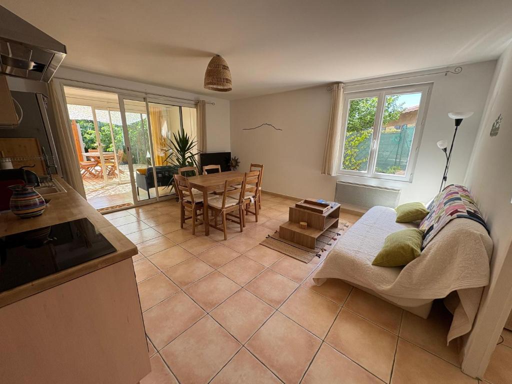 Una cocina y una sala de estar con un sofá y una mesa. en Logement avec jardin et terrain de pétanque privé, en Venelles