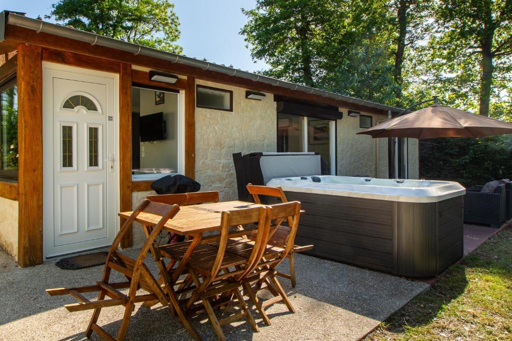 谢尔河畔塞勒La Salamandre - maison avec jacuzzi的庭院设有热水浴池、桌子和椅子。