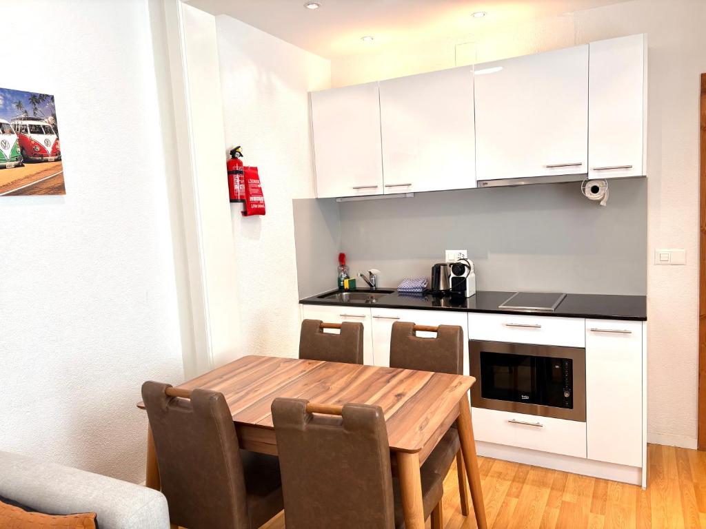 a kitchen with a wooden table and white cabinets at Akomo Bern in Bern