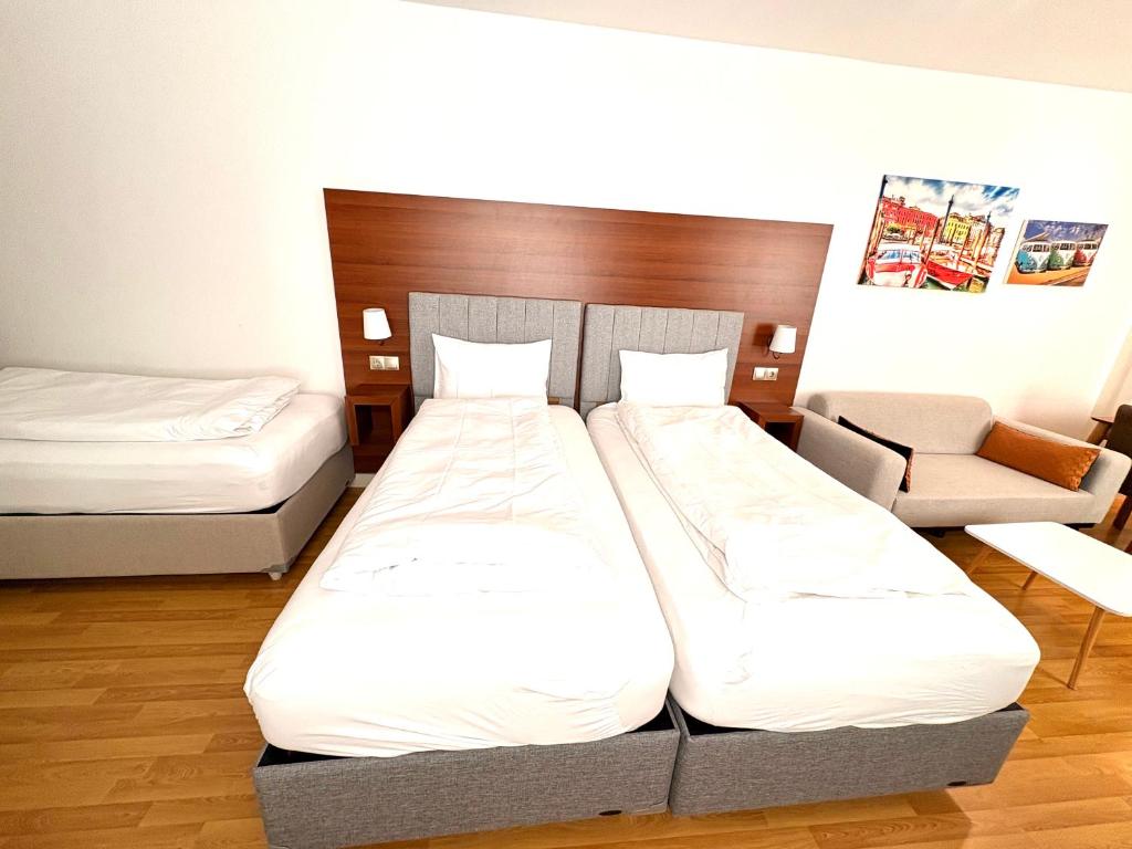 a hotel room with two beds and a chair at Akomo Bern in Bern
