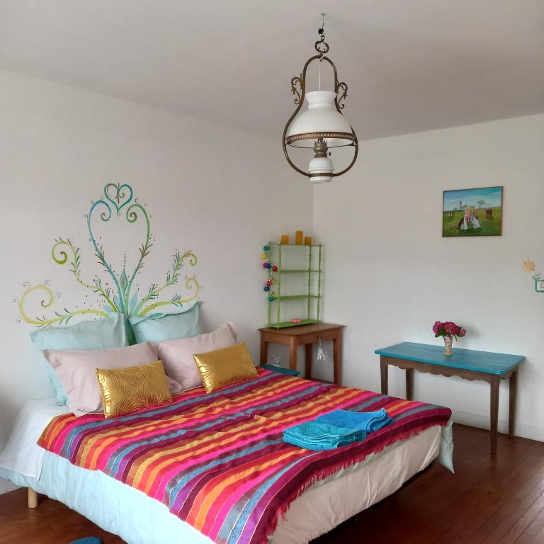 a bedroom with a bed with a colorful blanket at Chambres d'Hôtes Couleurs d'Elvine in Coutances