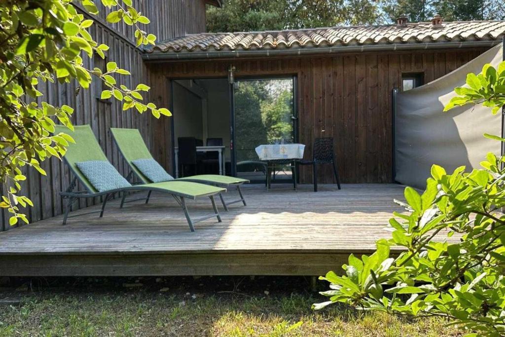 une terrasse en bois avec deux chaises et une table dans l'établissement Beautiful house with garden - near park, à Gujan-Mestras