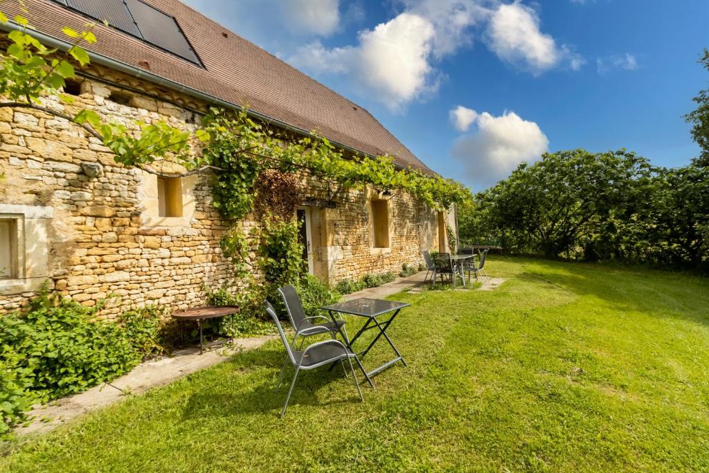 a stone house with chairs and a table in the yard at Maison De Vacances Chêne in Auriac-du-Périgord