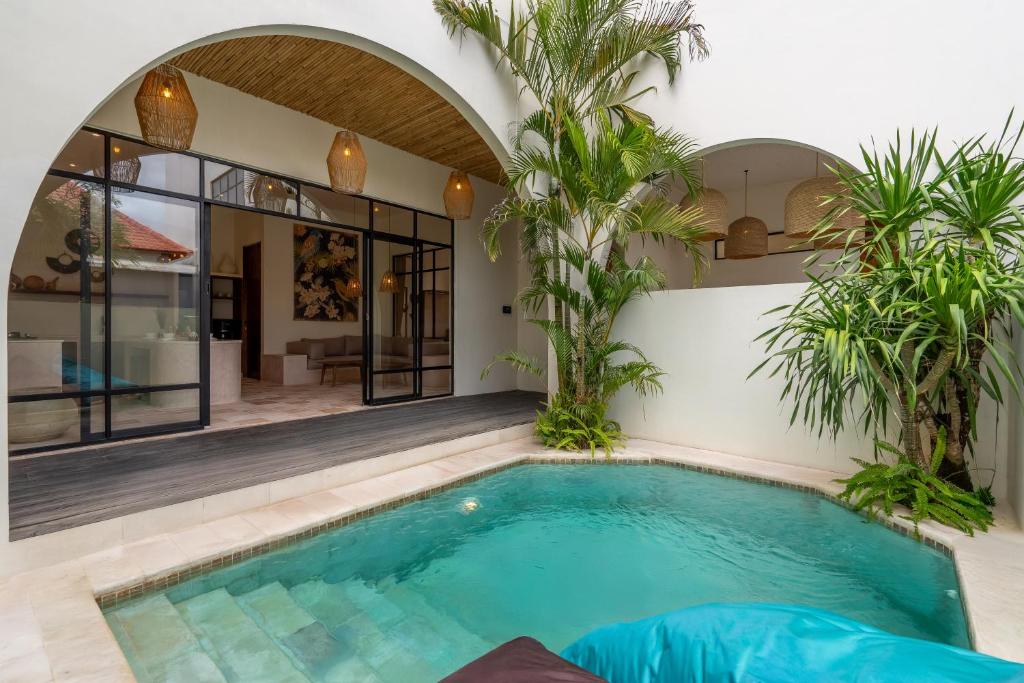een binnenzwembad in een huis met palmbomen bij Sofia Villa by betterplace in Canggu