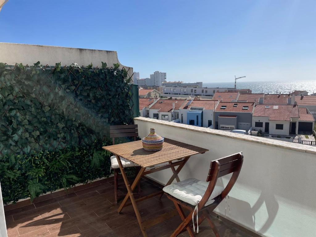 ein Tisch und Stühle auf einem Balkon mit Blick auf das Meer in der Unterkunft Santa Cruz Sunset in A dos Cunhados