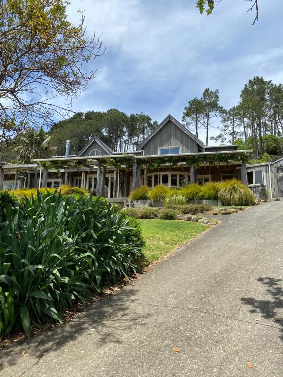 a house with a garden in front of a driveway at Above the Bay in Hahei