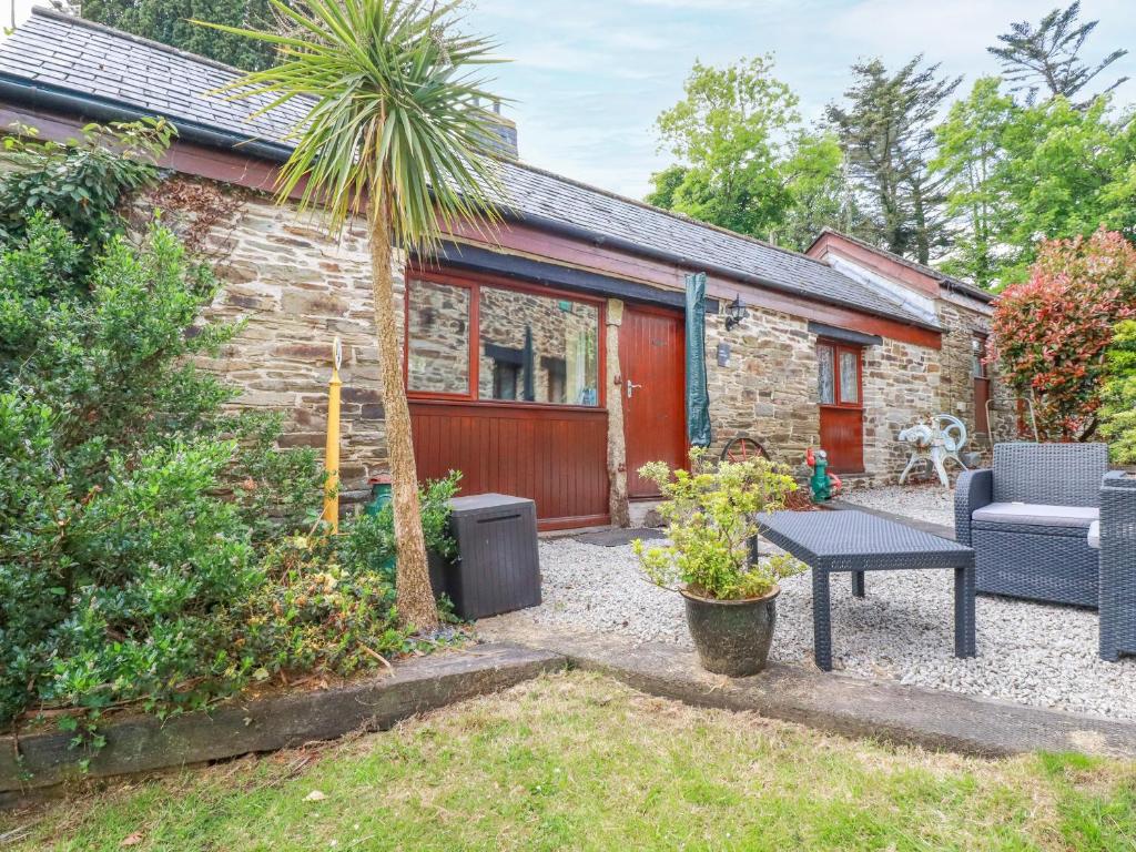 a stone cottage with a palm tree and a table at Barn Cottage in Liskeard