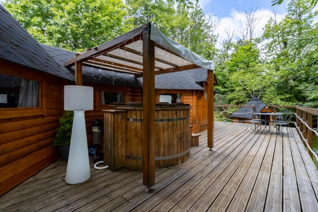 une terrasse en bois avec un bain à remous et une pergola dans l'établissement Grand Kota Avec Bain Nordique, à Saint-Cybranet